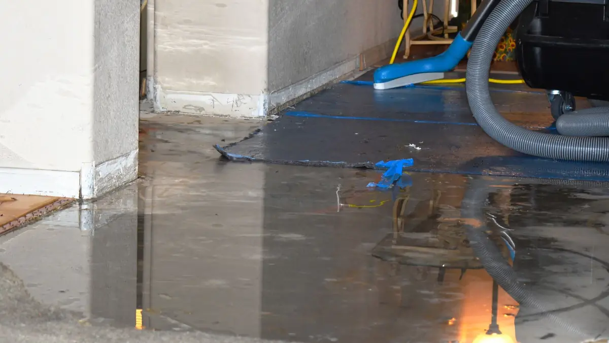 Standing water being pumped from a basement floor with a hose
