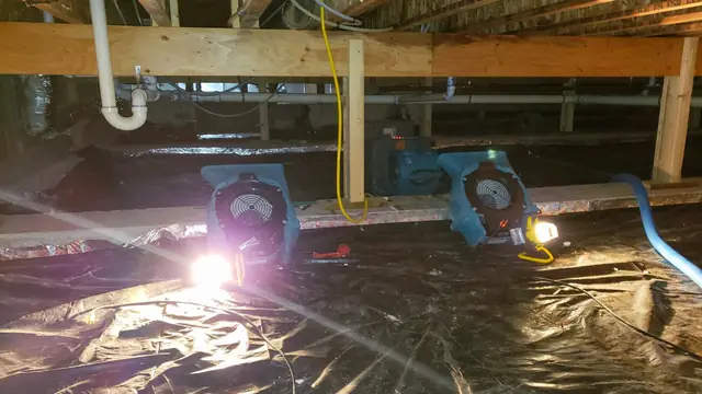 Air movers drying a crawl space under exposed floor joists